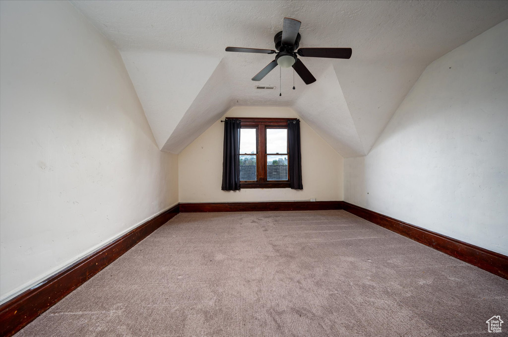 Additional living space with carpet flooring, ceiling fan, a textured ceiling, and lofted ceiling