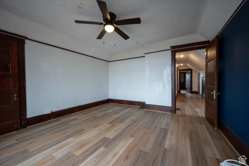 Unfurnished room featuring a textured ceiling, ceiling fan, hardwood / wood-style floors, and vaulted ceiling