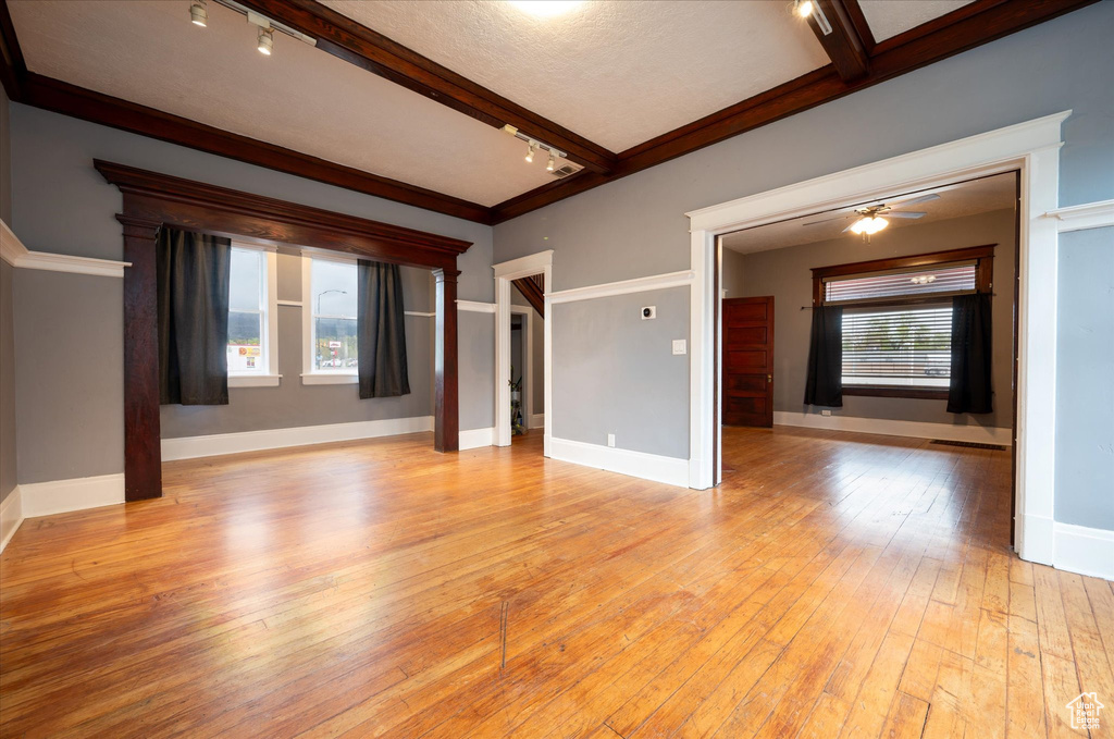 Spare room featuring light hardwood / wood-style floors, ceiling fan, and track lighting