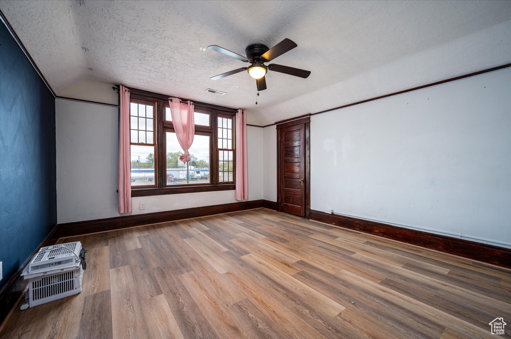 Empty room with ceiling fan, hardwood / wood-style flooring, and a textured ceiling