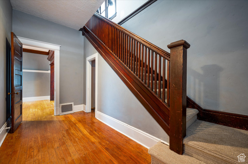 Stairs with a textured ceiling and hardwood / wood-style floors