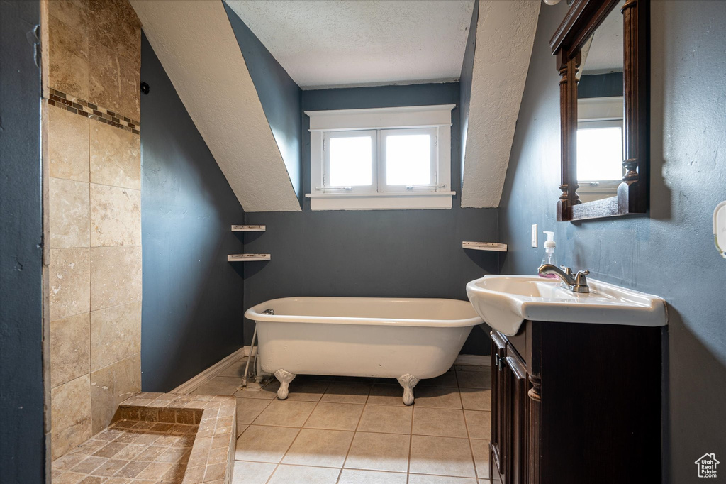 Bathroom featuring tile floors, vanity, tile walls, a bathing tub, and a textured ceiling