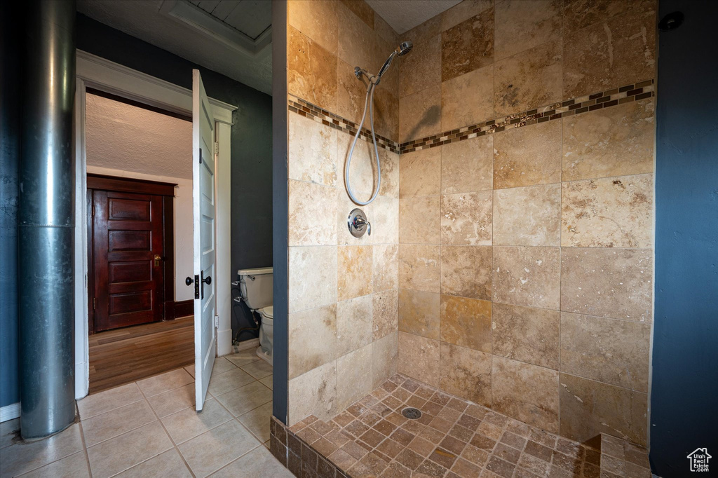 Bathroom featuring toilet, tile floors, and tiled shower