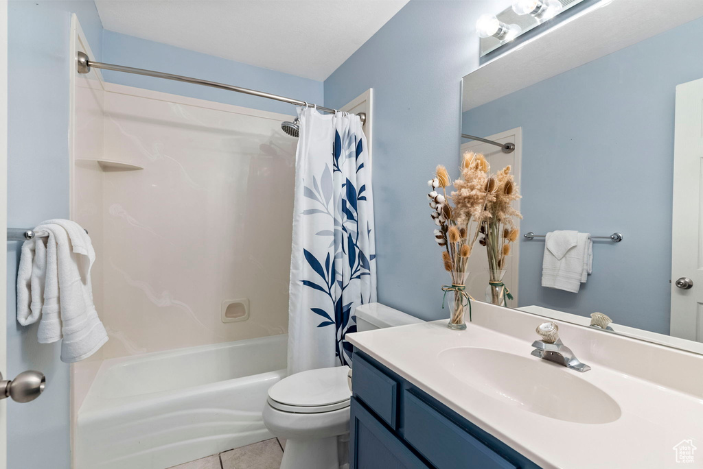 Full bathroom featuring tile floors, vanity, toilet, and shower / bathtub combination with curtain