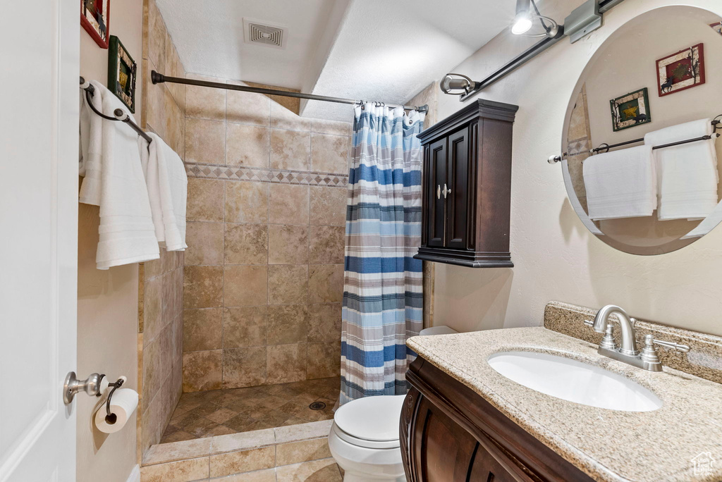 Bathroom with a shower with shower curtain, toilet, tile floors, and vanity
