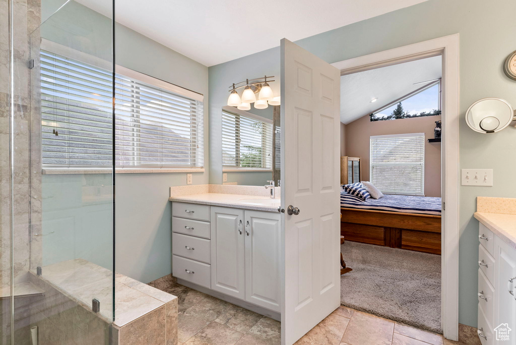 Bathroom featuring vaulted ceiling, a wealth of natural light, vanity, and tile flooring