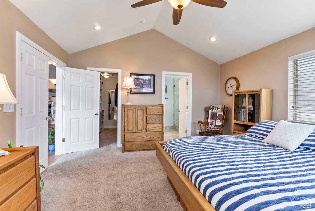 Bedroom featuring light colored carpet, vaulted ceiling, ceiling fan, and ensuite bathroom