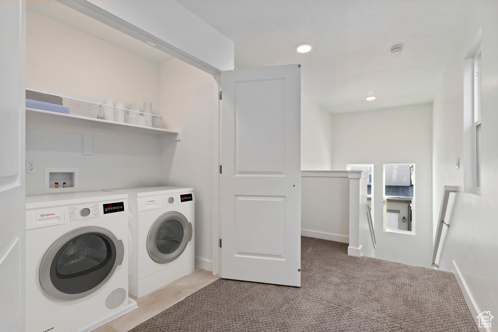 Clothes washing area featuring light colored carpet, washer and dryer, and hookup for a washing machine
