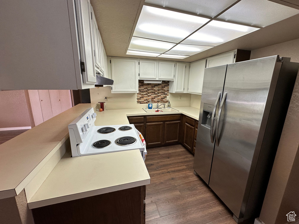 Kitchen featuring range, sink, tasteful backsplash, dark wood-type flooring, and stainless steel refrigerator with ice dispenser