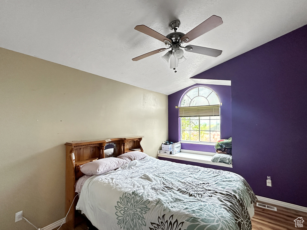 Bedroom with wood-type flooring, ceiling fan, and vaulted ceiling