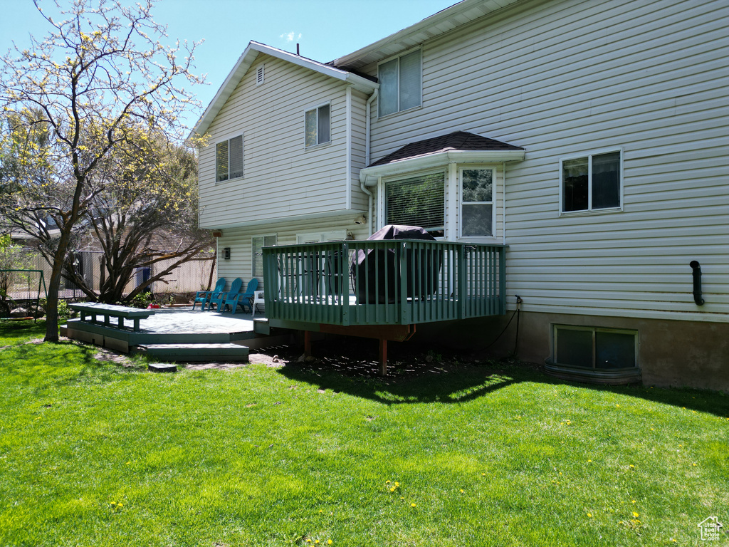 Back of property featuring a yard and a wooden deck