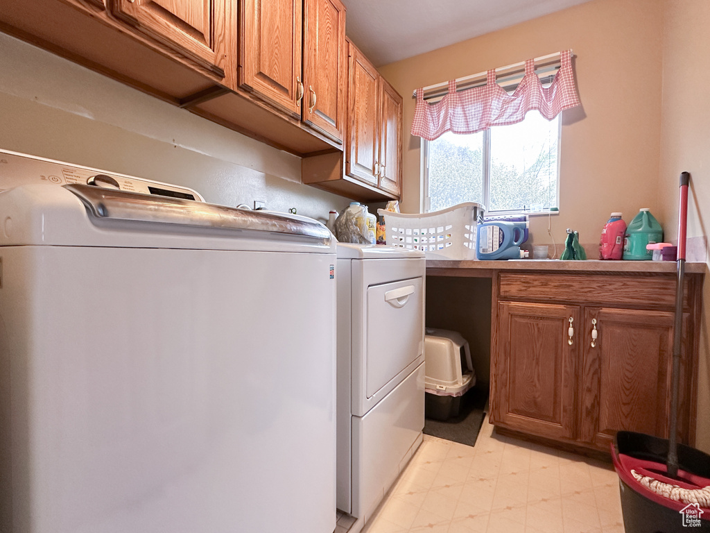 Laundry area featuring cabinets, light tile floors, and washer and clothes dryer