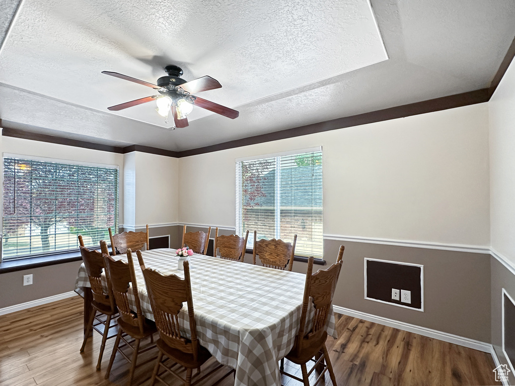Dining room featuring ceiling fan, hardwood / wood-style flooring, and a textured ceiling