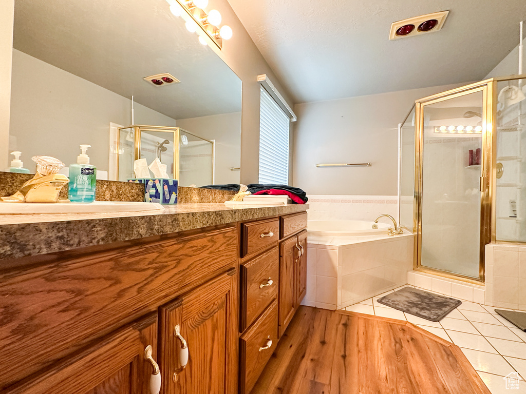 Bathroom featuring wood-type flooring, dual bowl vanity, and separate shower and tub
