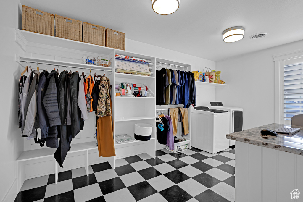 Walk in closet with independent washer and dryer and dark tile floors