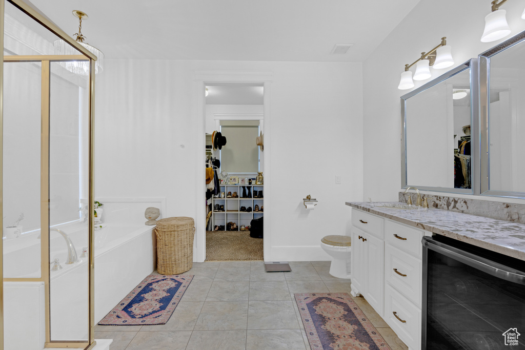 Bathroom featuring wine cooler, tile floors, toilet, and a bath
