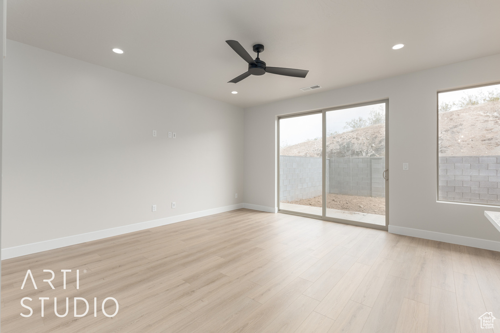 Empty room with ceiling fan and light hardwood / wood-style flooring