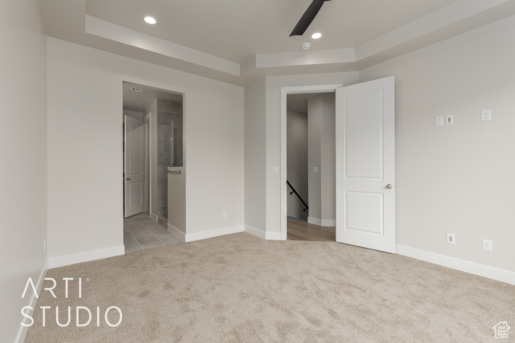 Carpeted spare room featuring a raised ceiling