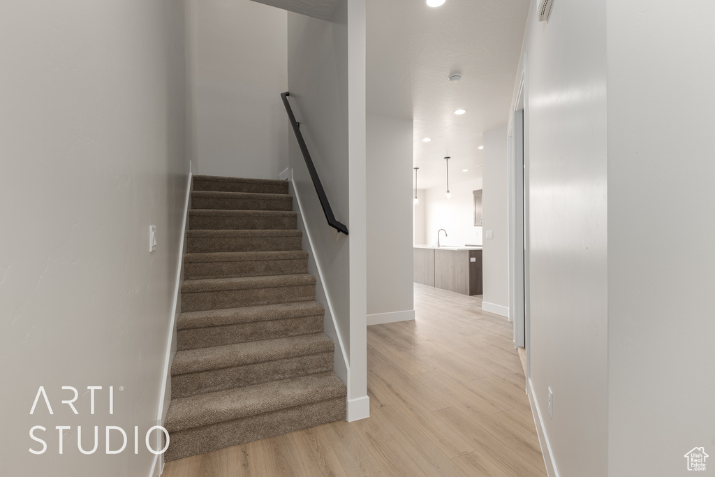 Stairs featuring sink and light wood-type flooring