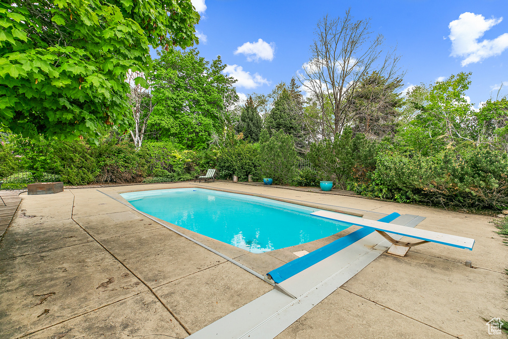 View of swimming pool featuring a diving board and a patio