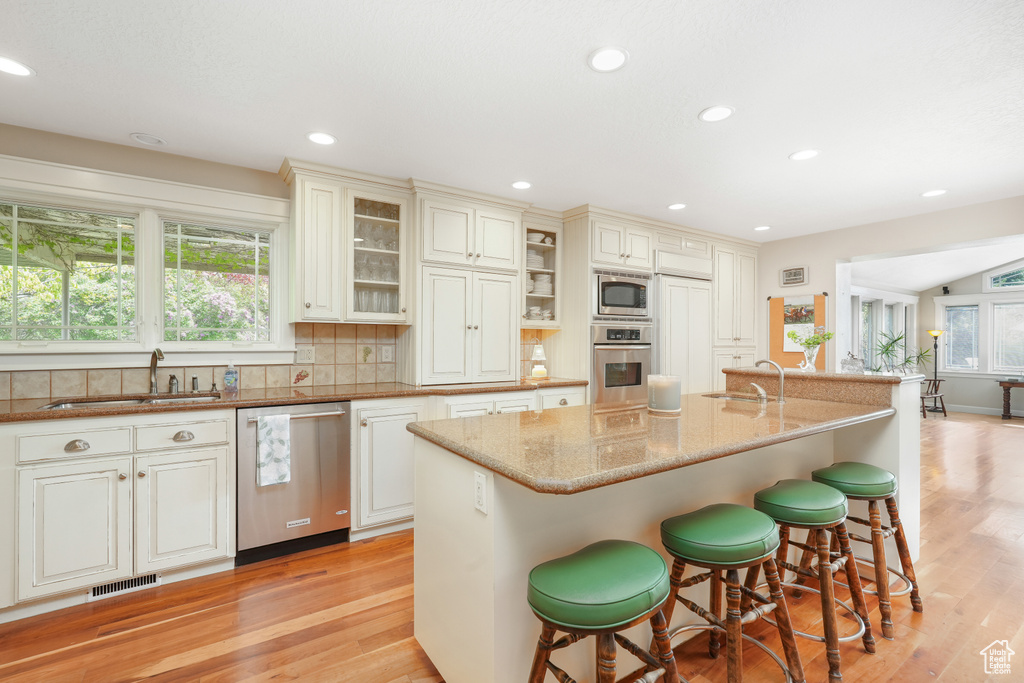 Kitchen featuring plenty of natural light, sink, stainless steel appliances, and a kitchen island with sink