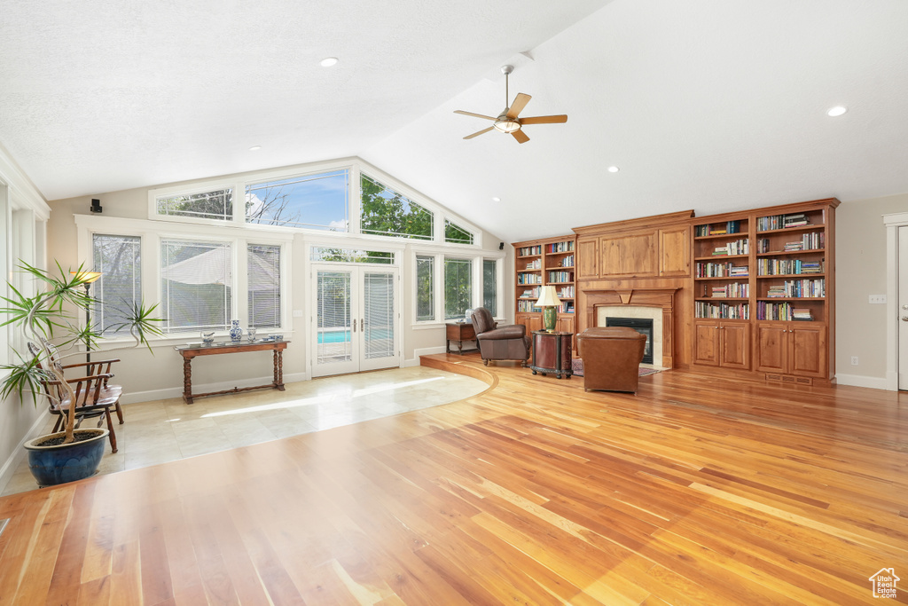Living room featuring high vaulted ceiling, ceiling fan, light hardwood / wood-style floors, and built in features