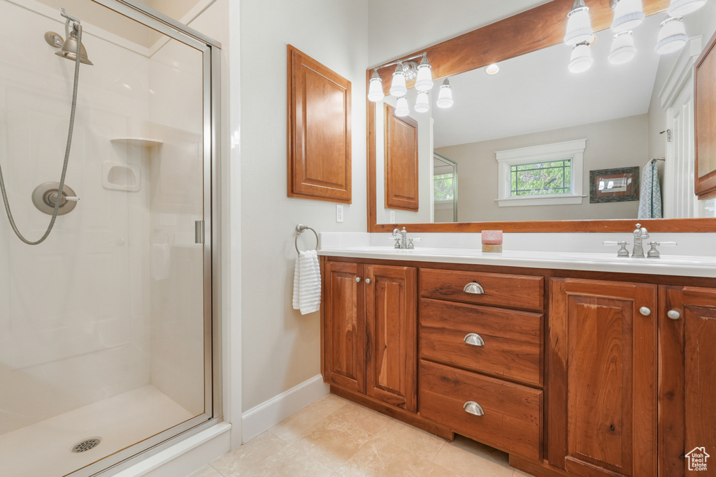 Bathroom with dual sinks, tile floors, large vanity, and a shower with shower door