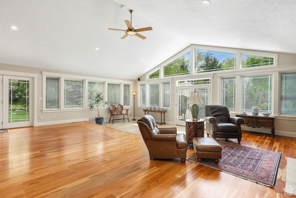Interior space with plenty of natural light, high vaulted ceiling, ceiling fan, and light wood-type flooring