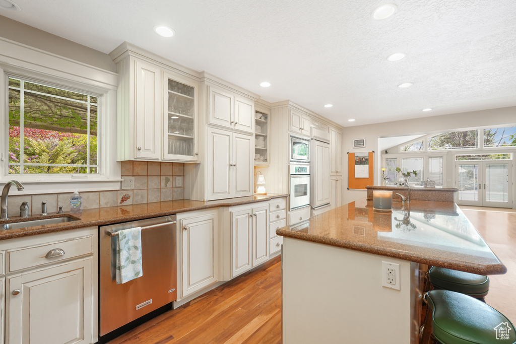 Kitchen with appliances with stainless steel finishes, light hardwood / wood-style flooring, sink, and tasteful backsplash
