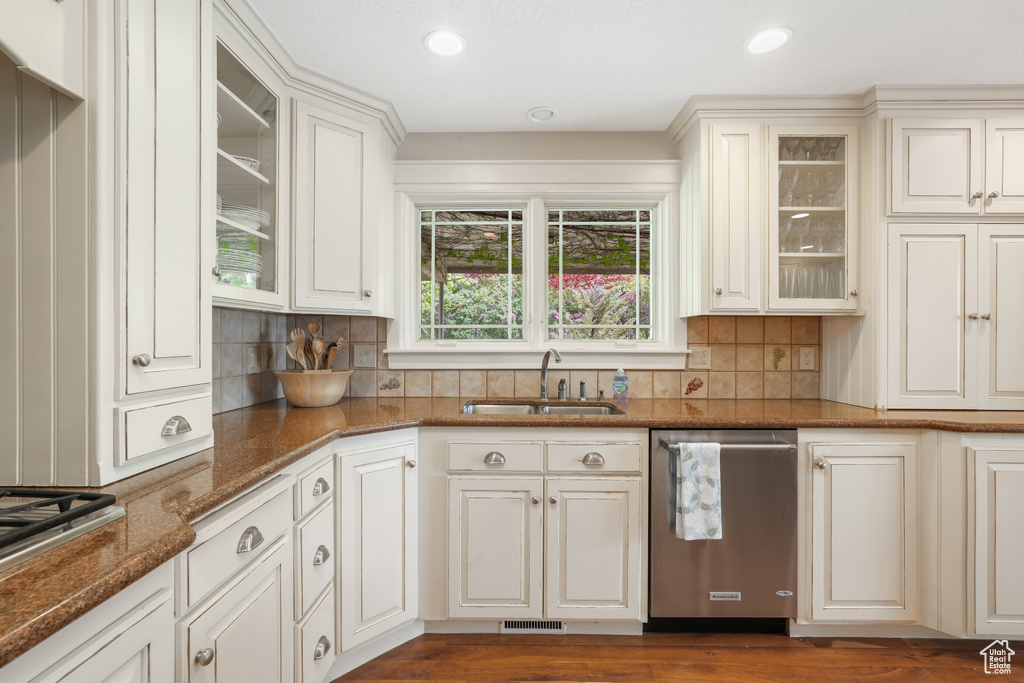 Kitchen featuring dark hardwood / wood-style flooring, stainless steel appliances, sink, tasteful backsplash, and dark stone countertops