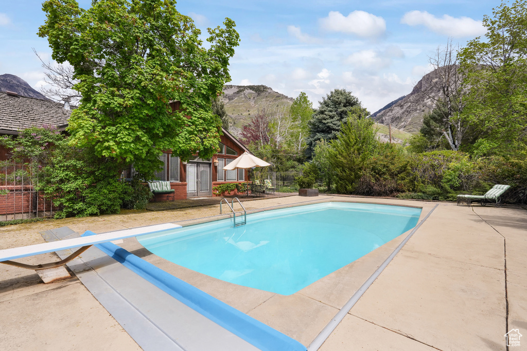 View of pool with a patio area, a mountain view, and a diving board