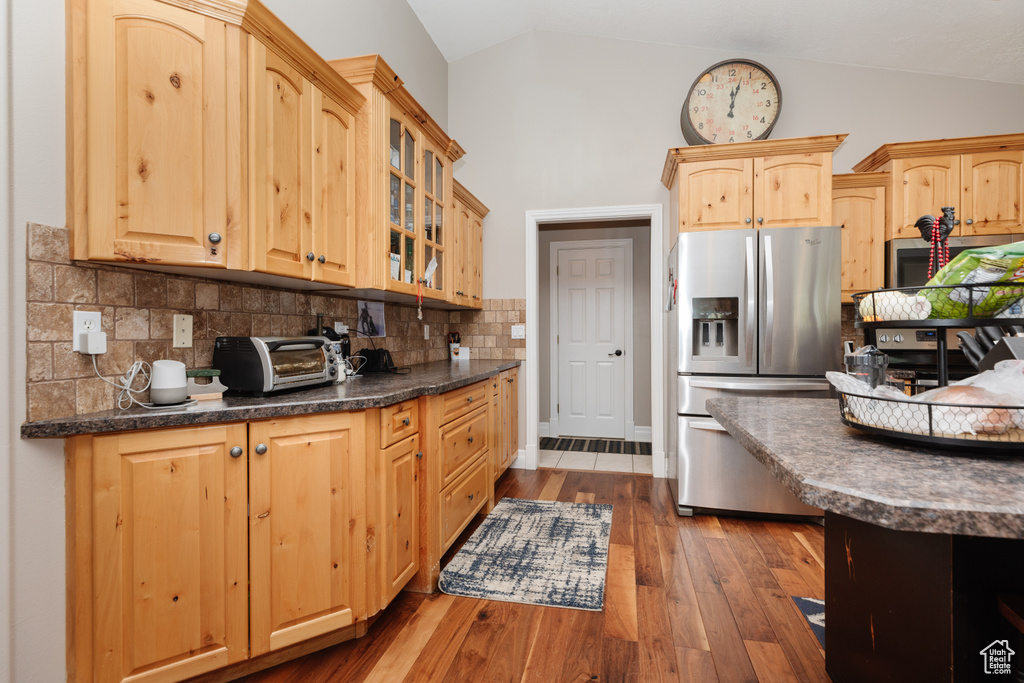 Kitchen with lofted ceiling, tasteful backsplash, hardwood / wood-style flooring, and stainless steel appliances
