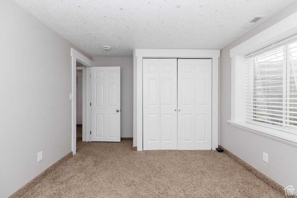 Unfurnished bedroom with a closet, carpet flooring, and a textured ceiling