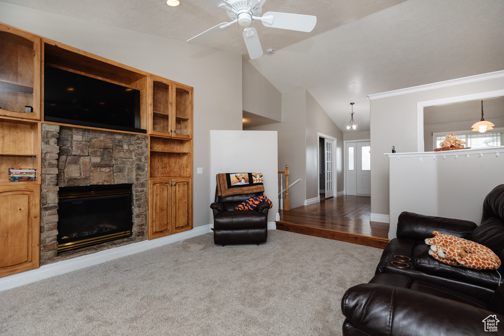 Carpeted living room featuring lofted ceiling, a fireplace, and ceiling fan