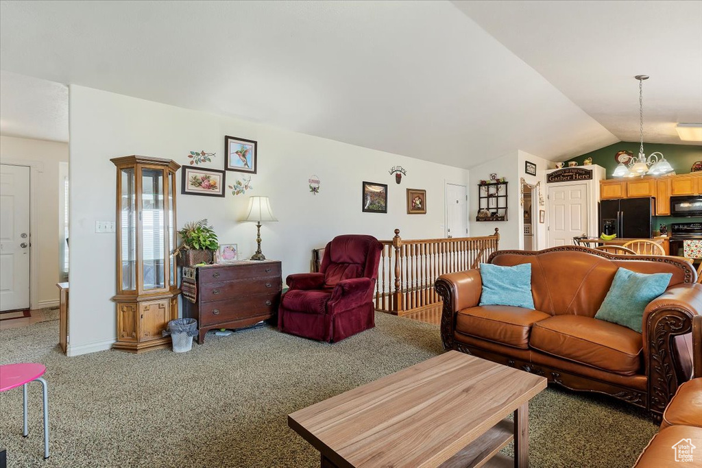 Living room with carpet flooring, an inviting chandelier, and lofted ceiling