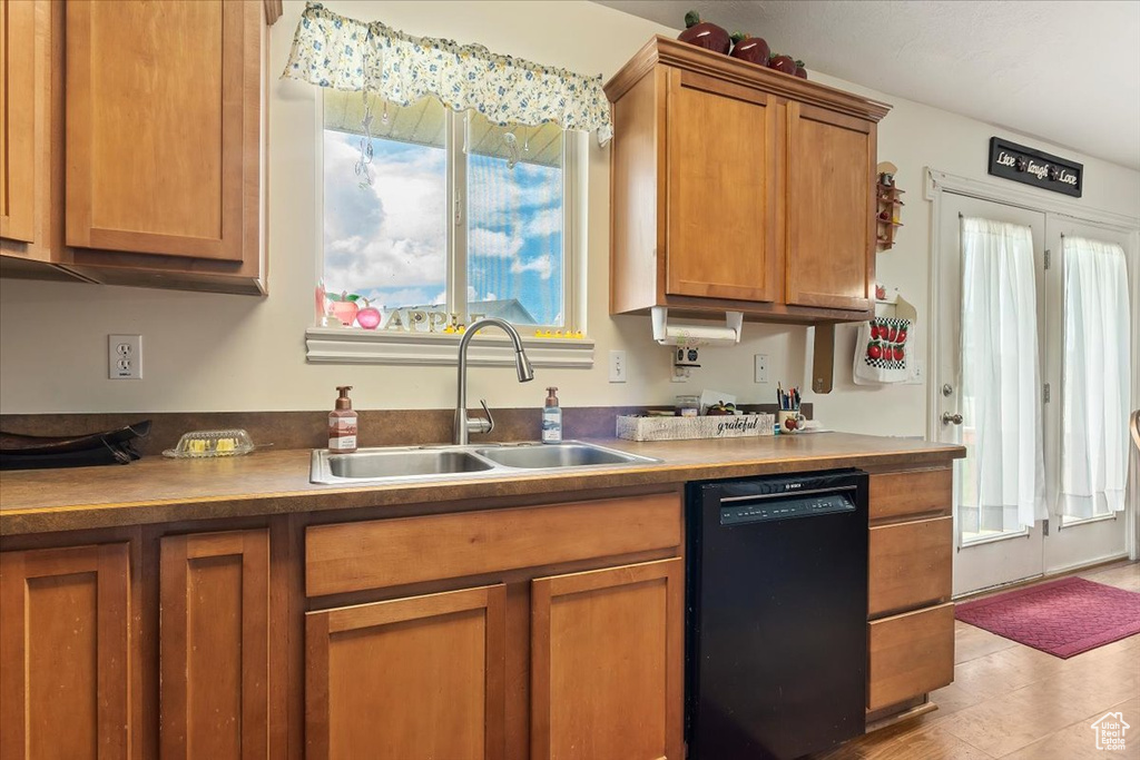 Kitchen featuring sink, light tile floors, and black dishwasher