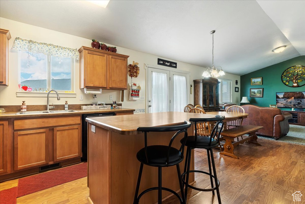 Kitchen with a kitchen island, sink, light wood-type flooring, decorative light fixtures, and lofted ceiling