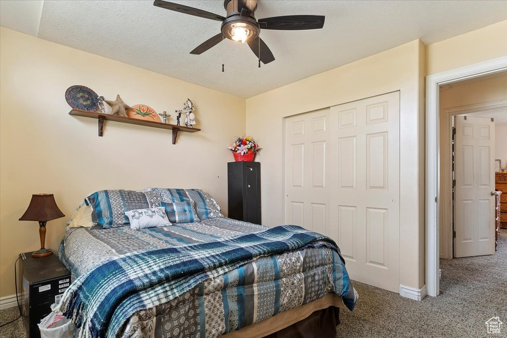 Carpeted bedroom featuring a closet, ceiling fan, and a textured ceiling