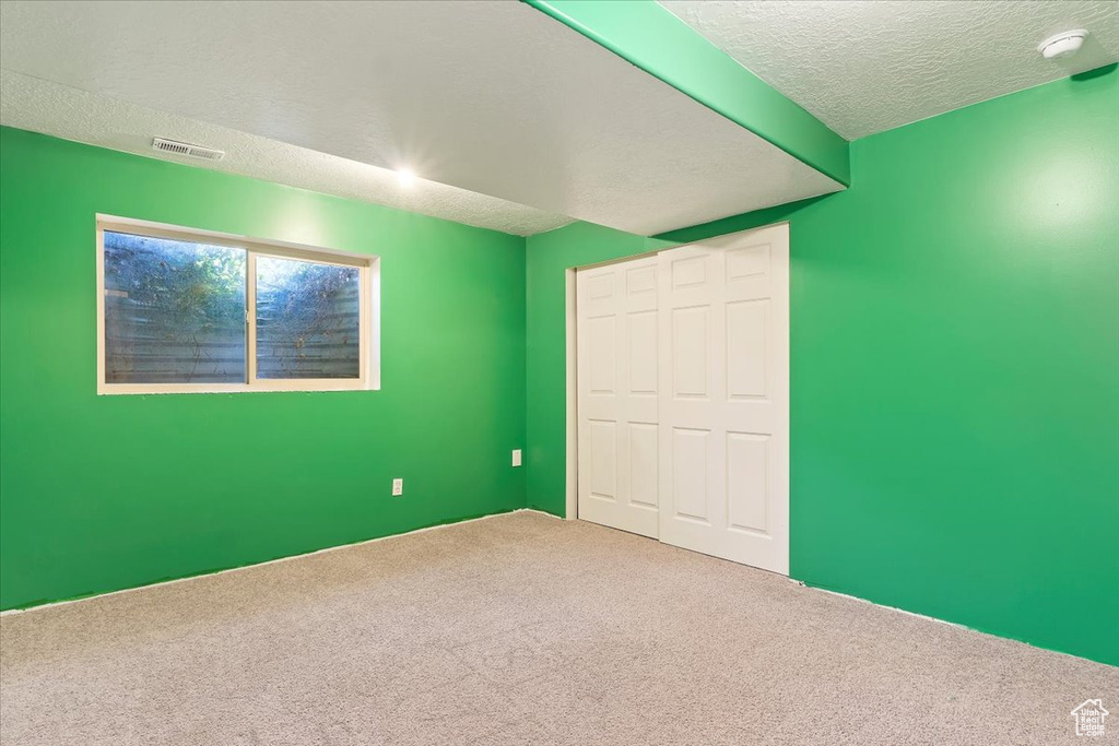 Unfurnished bedroom with a closet, a textured ceiling, and carpet