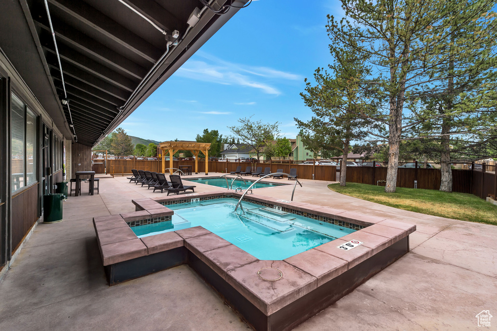 View of swimming pool with an in ground hot tub and a patio area