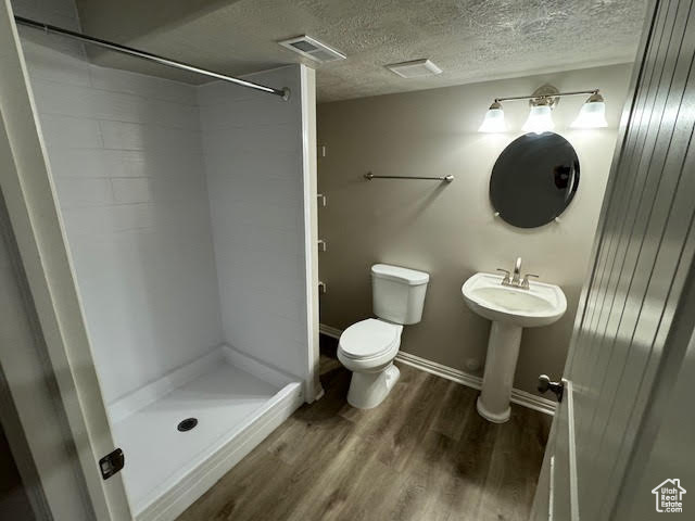 Bathroom featuring a textured ceiling, sink, walk in shower, toilet, and hardwood / wood-style flooring