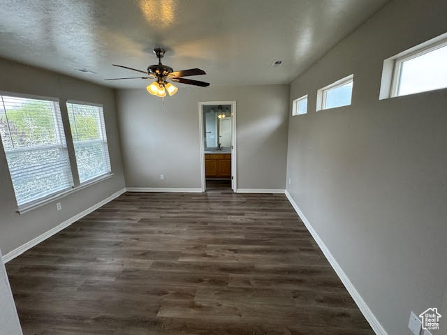 Empty room with ceiling fan and dark wood-type flooring