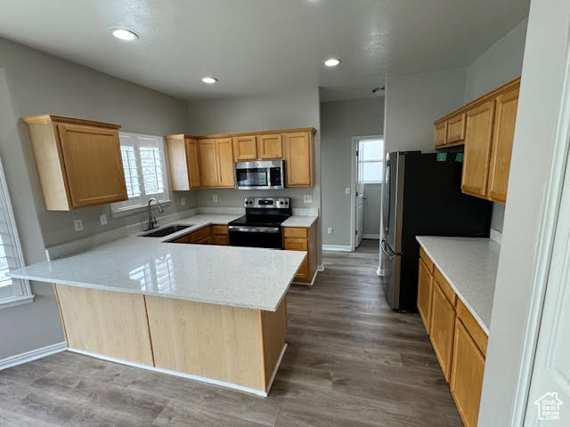 Kitchen with hardwood / wood-style floors, sink, appliances with stainless steel finishes, and kitchen peninsula