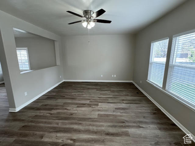 Empty room with ceiling fan and dark hardwood / wood-style flooring