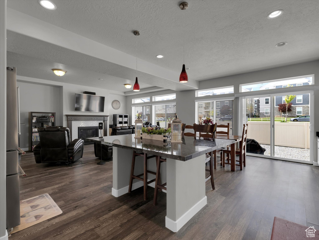 Kitchen with dark hardwood / wood-style floors, pendant lighting, a breakfast bar, and a fireplace