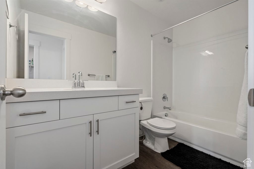 Full bathroom featuring vanity, toilet, hardwood / wood-style flooring, and shower / washtub combination