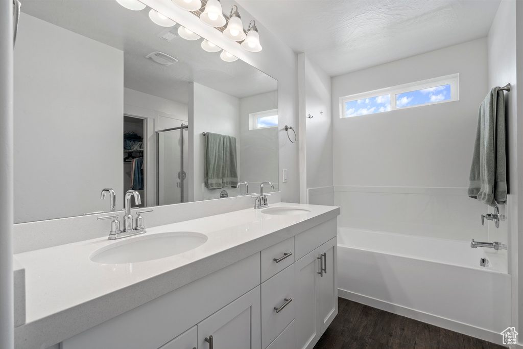 Bathroom featuring hardwood / wood-style floors, large vanity, a bath, and double sink