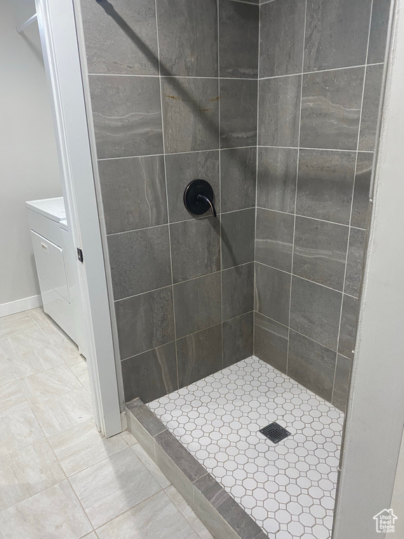 Bathroom with tile flooring, vanity, and a tile shower