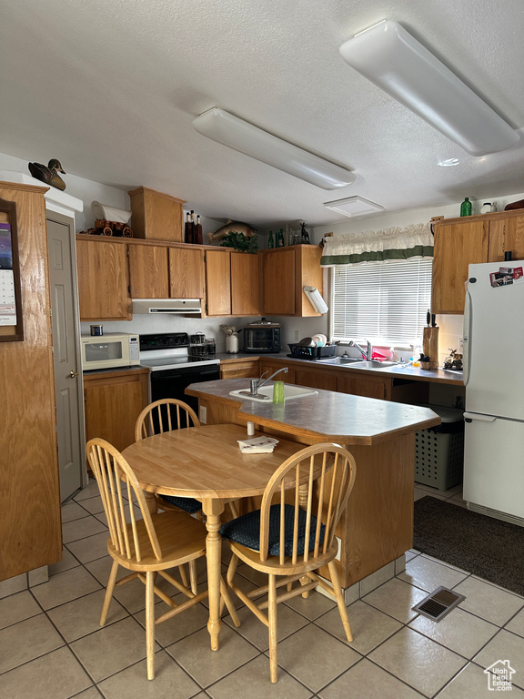 Kitchen with extractor fan, white appliances, and light tile floors