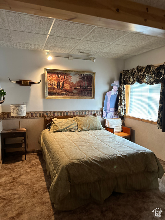 Bedroom with a paneled ceiling and carpet floors